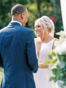 Bride smiling as she holds grooms hand at the end of the aisle at a Channel Side Wedding in Palm Coast, Florida. Taken by Ashley Dye Photography, a Jacksonville, Florida Wedding Photographer.