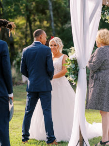 Bride smiling as she holds grooms hand during vows at a Channel Side Wedding in Palm Coast, Florida. Taken by Ashley Dye Photography, a Jacksonville, Florida Wedding Photographer.