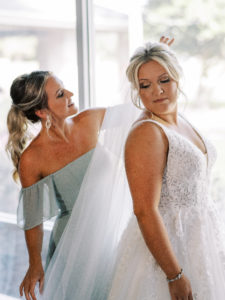 Bridesmaid adjusting the Bride's veil at her Channel Side Wedding in Palm Coast, Florida. Taken by Ashley Dye Photography, a Jacksonville, Florida Wedding Photographer.